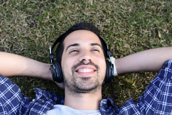 Giovane che ascolta musica con le cuffie nel parco . — Foto Stock