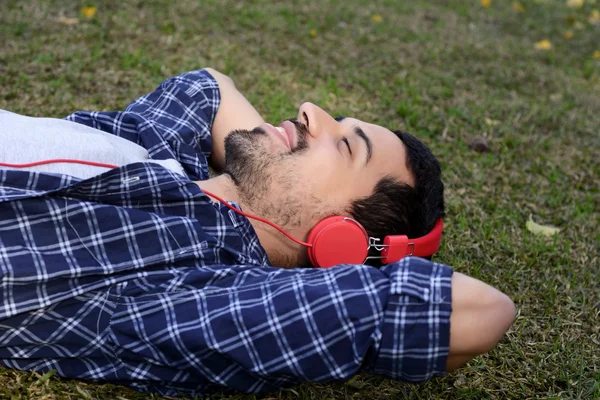 Giovane che ascolta musica con le cuffie nel parco . — Foto Stock