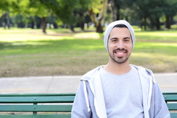 公園のベンチに座っている若いラテン男. — ストック写真