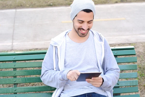 Joven usando tableta sentada en el banco del parque . —  Fotos de Stock