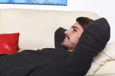 mutlu genç adam kanepede yatan ve rahatlatıcı