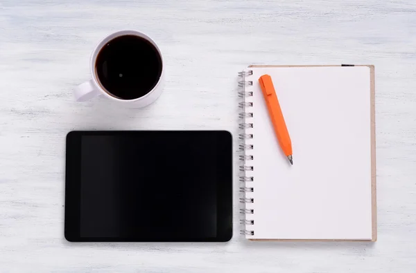Tablet, een koffiekopje en een notitieboek. — Stockfoto