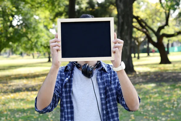 Young man with black headphones holding chalkboard . — Stock Photo, Image