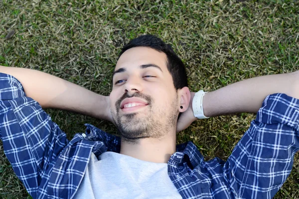 Joven latino relajado tumbado en la hierba — Foto de Stock