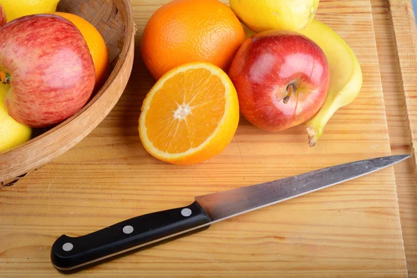 Frutas frescas y cuchillo sobre mesa de madera. Concepto de alimentación saludable — Foto de Stock