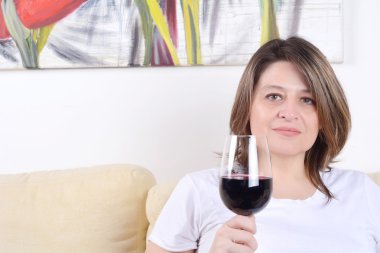 Kadın bir kadeh şarap ile kanepede rahat.