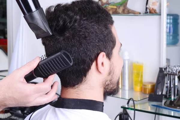 Mann frisiert und trocknet sich die Haare mit einem Föhn. — Stockfoto