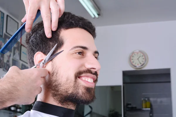 Young man having a haircut with scissors.