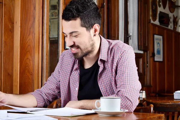 Estudiante latino leyendo notas y tomando café . — Foto de Stock
