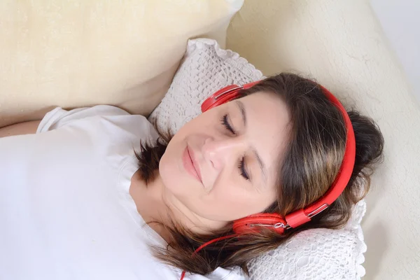 Donna che ascolta musica sul divano . — Foto Stock