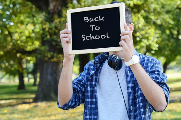 Ung man med svarta hörlurar håller svarta tavlan — Stockfoto