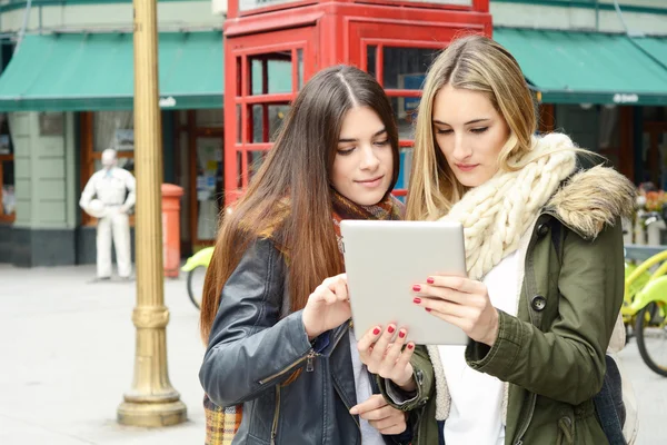 Dos novias jóvenes en un viaje juntas y usando la tableta . —  Fotos de Stock