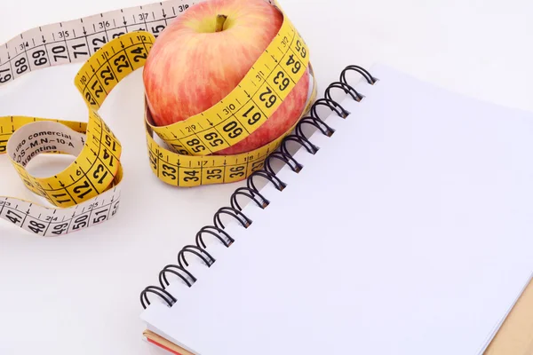 An apple and measuring tape on notepad. Royalty Free Stock Photos