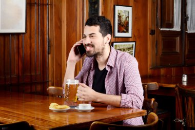 Latince bardak bira ve atıştırmalıklar ile telefonda konuşan adam.