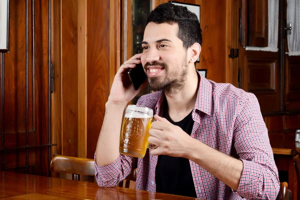 Uomo latino che parla al telefono con bicchiere di birra e snack . — Foto Stock