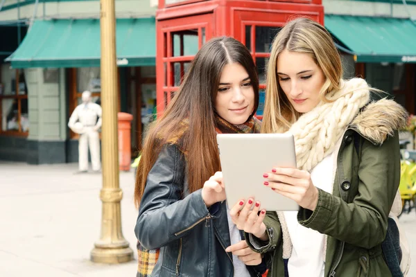 Dos novias jóvenes en un viaje juntas y usando la tableta . —  Fotos de Stock