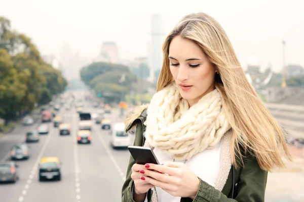 Ung kvinna skickar meddelanden med sin smartphone. — Stockfoto