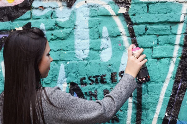 Женщина рисует граффити с распылительной краской на стене улицы . — стоковое фото