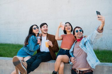 Birlikte eğlenen ve cep telefonuyla selfie çekerken eğlenen bir grup arkadaşın portresi. Yaşam tarzı ve arkadaşlık kavramı.