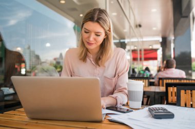 Bir kafede dizüstü bilgisayarıyla çalışan genç bir iş kadınının portresi. İş konsepti.