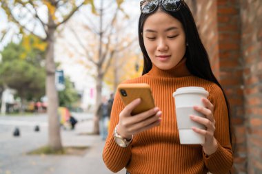 Sokakta cep telefonunu kullanan Asyalı bir kadın..