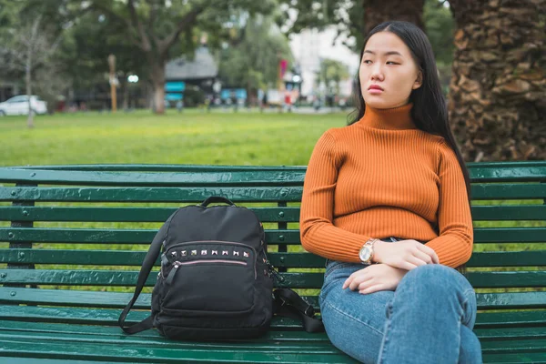 Mulher asiática sentada em um banco no parque — Fotografia de Stock