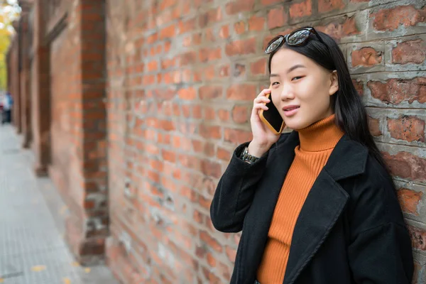 Asiatin benutzt ihr Handy auf der Straße. — Stockfoto
