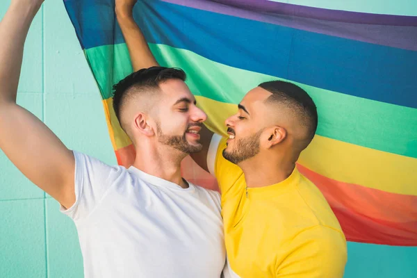 Gay pareja abrazando y mostrando su amor con arco iris bandera. —  Fotos de Stock