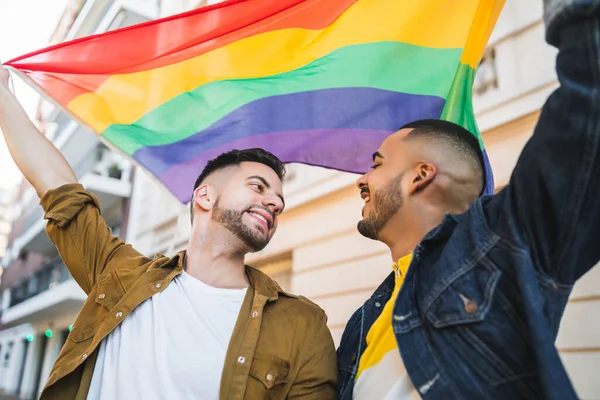 Gay pareja abrazando y mostrando su amor con arco iris bandera. —  Fotos de Stock