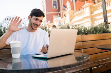 Dizüstü bilgisayarlı görüntülü sohbet kullanan genç adam.