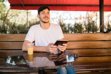 Genç adam kafede dijital tablet kullanıyor..