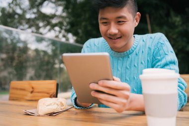 Asyalı adam dijital tabletini kullanıyor..