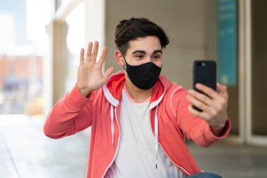 Genç adam cep telefonuyla video görüşmesi yapıyor..