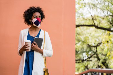 Elinde dijital tablet ve kahve tutan bir iş kadını..