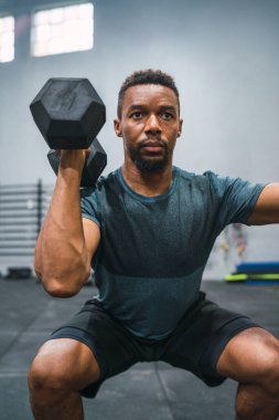 Crossfit sporcu dambılla egzersiz yapıyor.