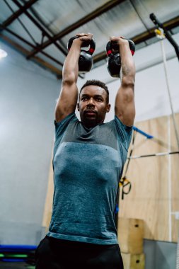 Atletik adam Crossfit kettlebel ile egzersiz yapıyor..