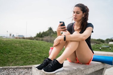 Atletik kadın telefonunu kullanıyor..