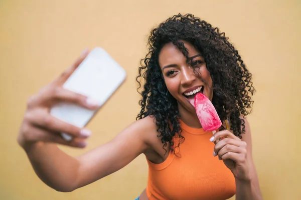 Afro mujer tomando selfies con teléfono mientras come helado. —  Fotos de Stock