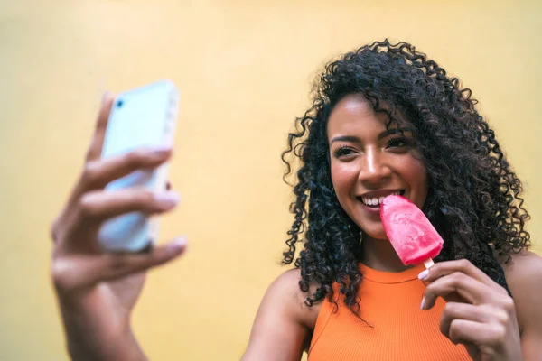 Afro mujer tomando selfies con teléfono mientras come helado. —  Fotos de Stock