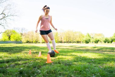 Genç bayan futbolcu sahada pratik yapıyor..