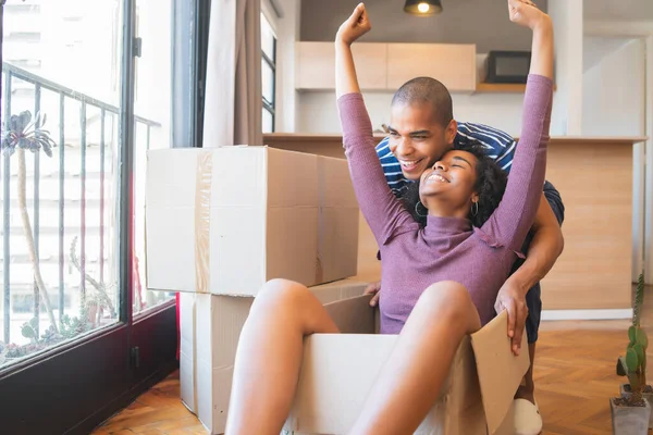 Latin couple having fun with cardboard boxes in new house. — Stock Photo, Image