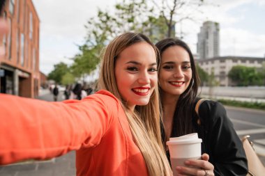 İki genç arkadaş dışarıda selfie çekiyorlar..