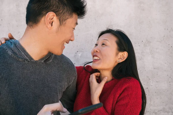 Asiatisches Paar schaut aufs Handy. — Stockfoto