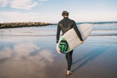 Sörfçü sörf tahtasıyla suya giriyor..