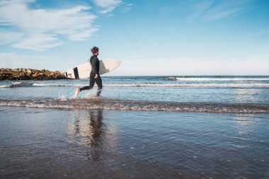 Sörfçü sörf tahtasıyla suya giriyor..
