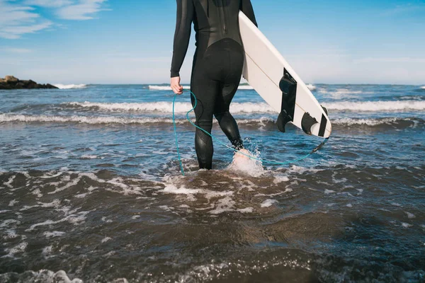 Серфер входит в воду со своей доской для серфинга. — стоковое фото
