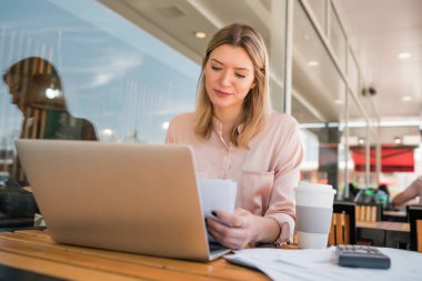 Dizüstü bilgisayarında çalışan genç bir iş kadını..