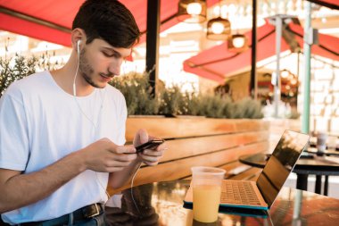 Kahve dükkanında cep telefonu kullanan genç adam..