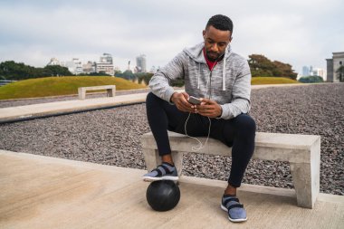 Atletik adam cep telefonunu kullanıyor..