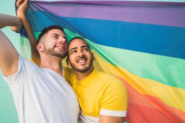 Eşcinsel çift gökkuşağı bayrağıyla sarılıyor ve sevgilerini gösteriyorlar.